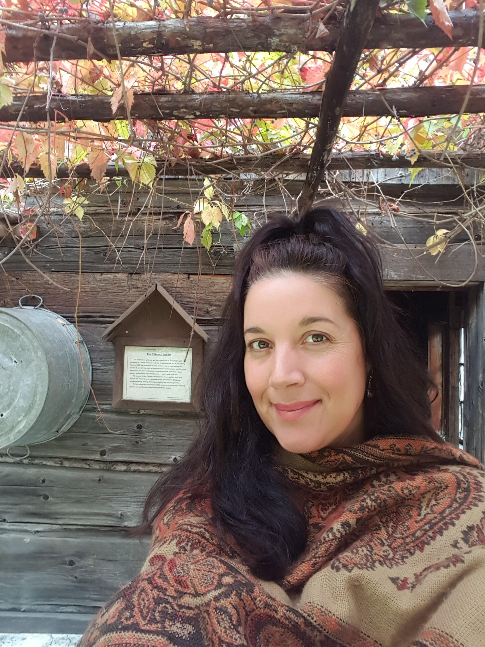 Diane Seamark outside a heritage log cabin, autumn